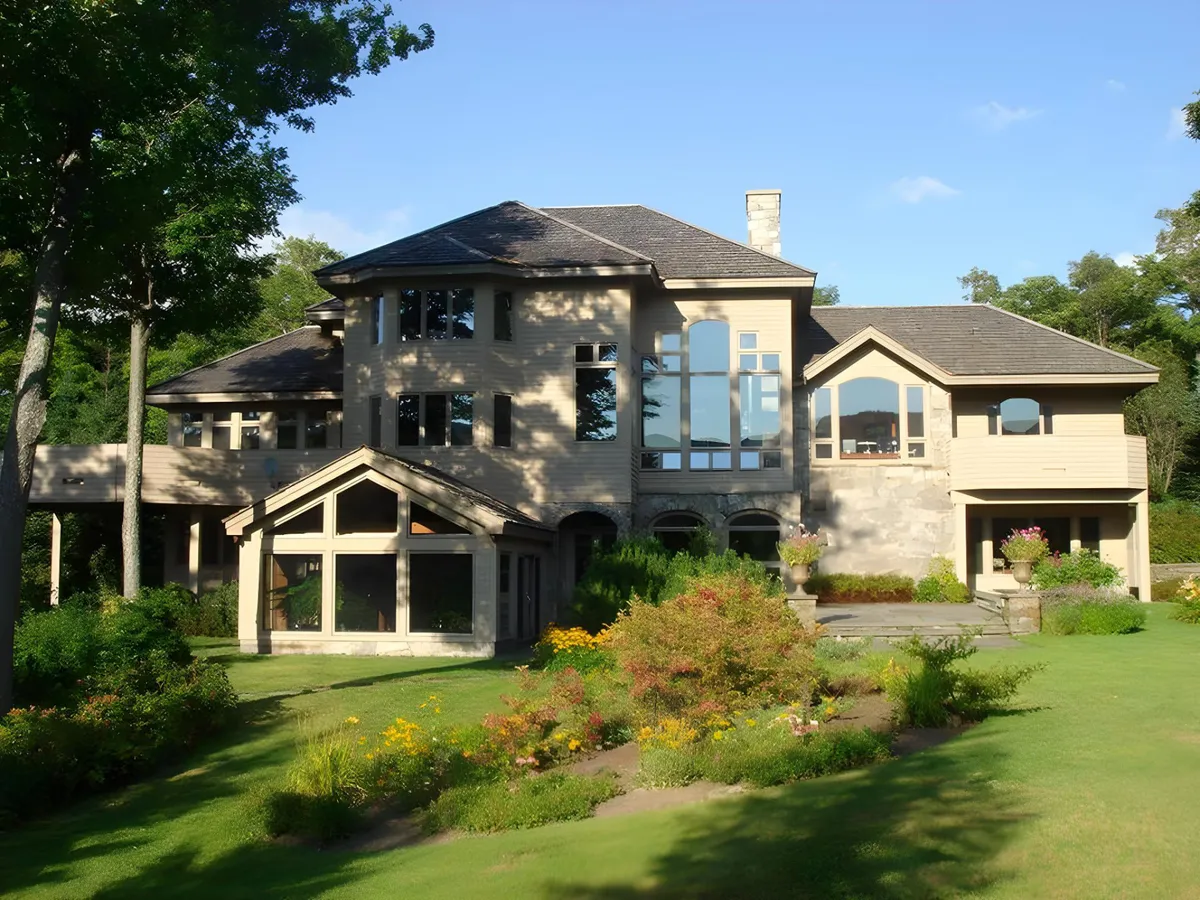 Featuring modern architectural design, large windows, and a beautifully landscaped garden, this image illustrates a welcoming exterior ideal for outdoor dining, family gatherings, or relaxing in the yard. The garden and patio space visually invite group activities and relaxation with mountain views in the background.