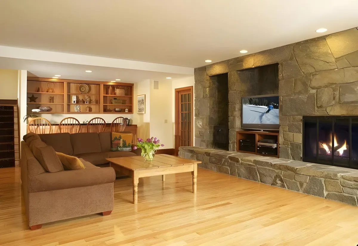 A warm, welcoming living area with a sofa, fireplace, coffee table, and television. The space is designed for both relaxation and entertainment, accommodating movie nights, game nights, and cozy gatherings with friends or family.