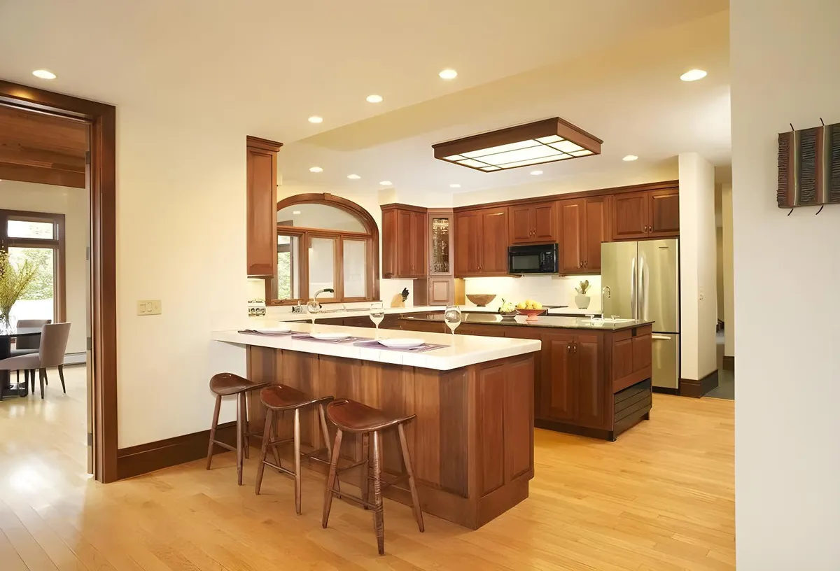A gourmet kitchen with an island countertop, bar stools, wood cabinetry, and modern appliances. The space is designed for both culinary creativity and sociable gatherings, inviting guests to cook, celebrate, and connect.