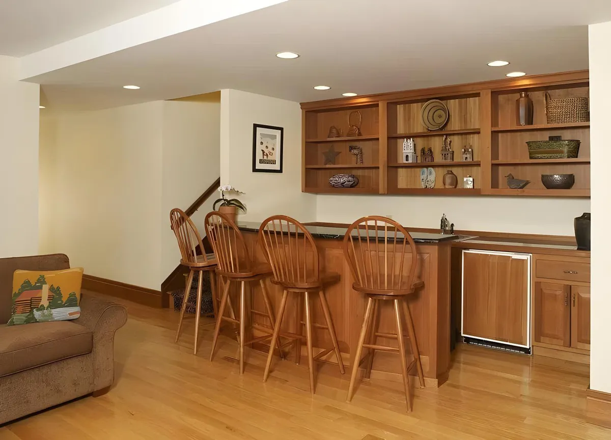 This inviting interior image features a bar area with stools and shelves displaying decorative items. The setting suggests a lively space for social interaction, with a relaxed yet energetic mood ideal for gatherings and entertainment.